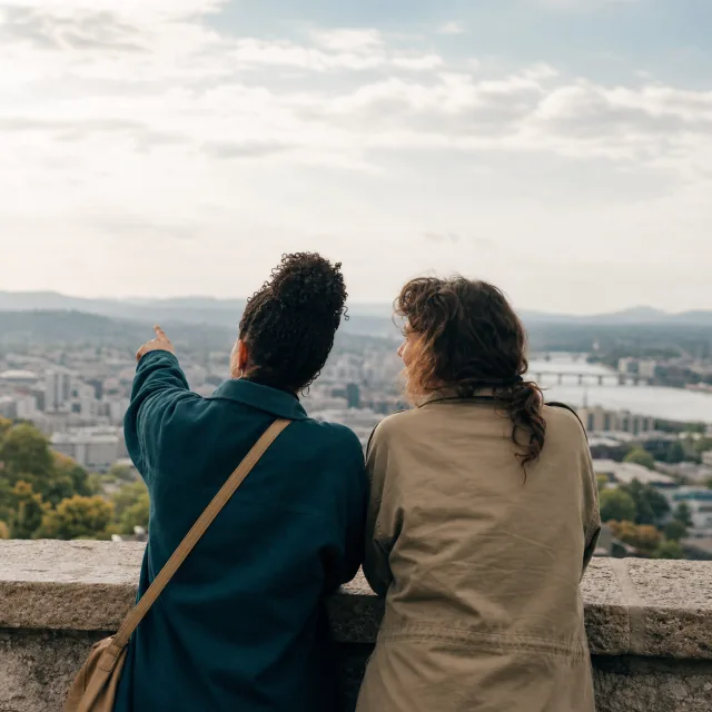 Two friends considering a broad city view from an overlook